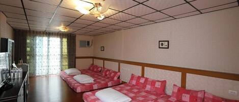 Ein Hotelzimmer mit zwei Betten, einem Fernseher und einem Fenster mit Vorhängen.