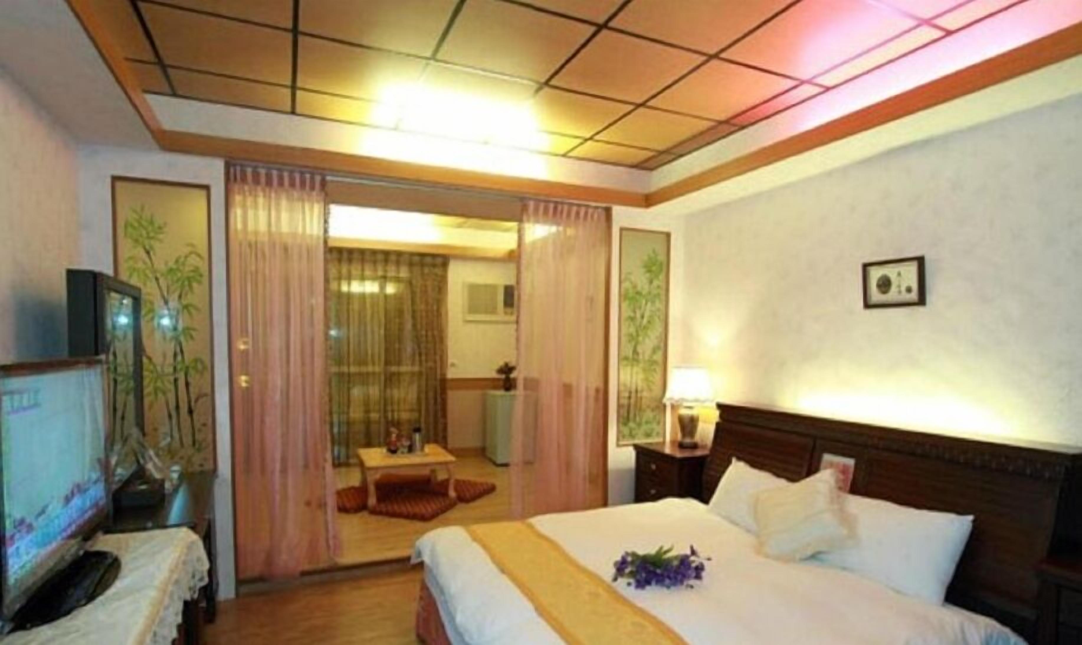 Een hotelkamer met een bed, een bureau, een stoel, een televisie en een spiegel.