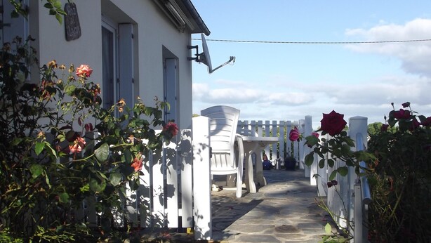 A pathway leading to a white building with a satellite dish, surrounded by rose bushes and a white picket fence. - Holiday house with sea view in Hanvec, quiet - 5 people. (Hanvec)