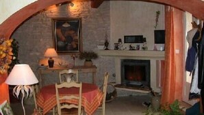 A cozy room with a fireplace, a dining table with chairs, and a painting on the wall. - Provencal farmhouse with pool  (Joucas)