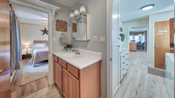 Une salle de bain moderne avec un meuble-lavabo, un évier et un miroir. Un motif en forme d’étoile décore le mur, et on y trouve également un meuble en bois.