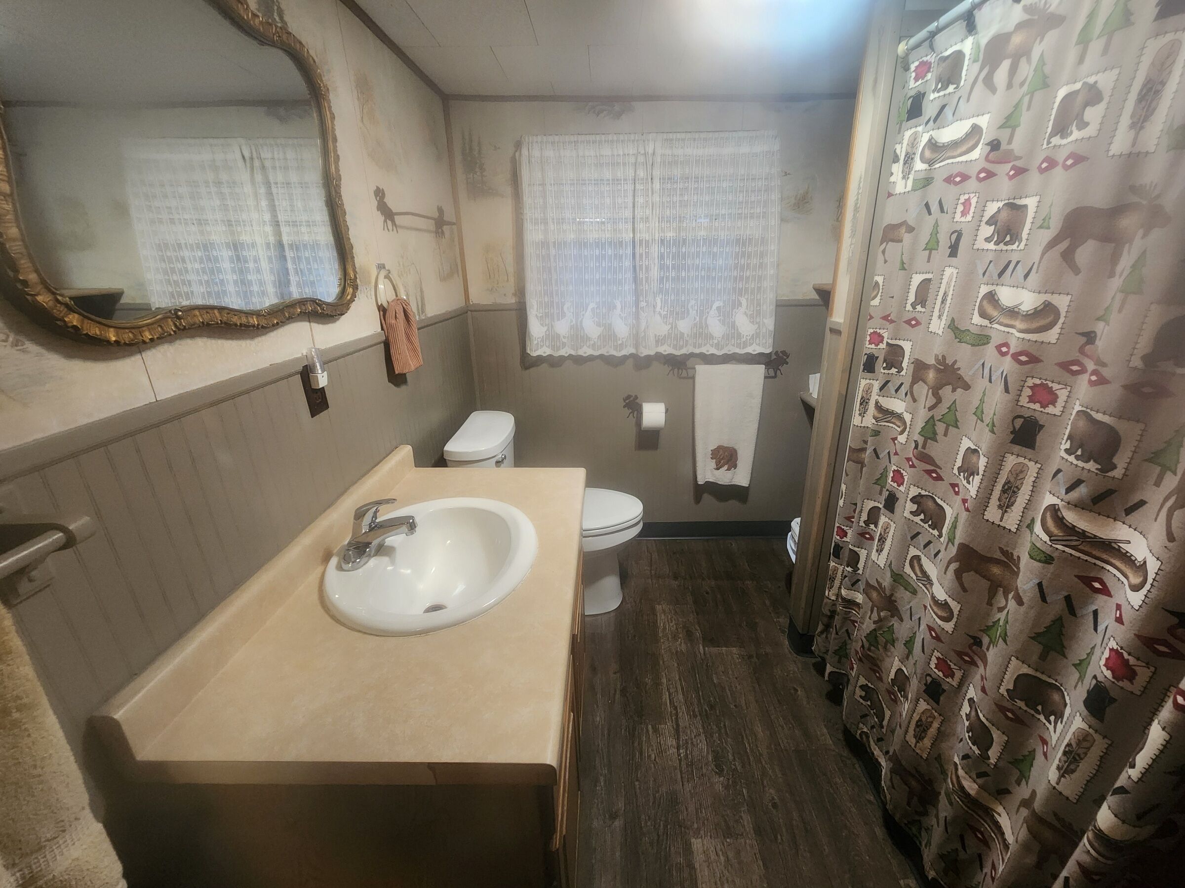 A compact bathroom with a sink, toilet, and shower curtain featuring animal prints.