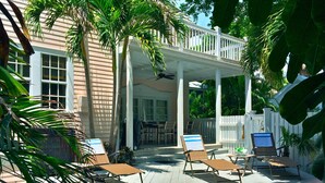 A poolside area with lounge chairs, a covered patio, and a view of the pool.