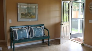 Une pièce avec un banc, une porte et un tableau encadré au mur.