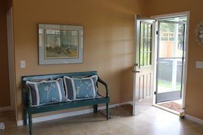 Une pièce avec un banc, une porte et un tableau encadré au mur.