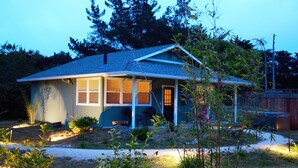 Une petite maison de plain-pied, avec un toit en pente, un porche à l’avant et une porte bien visible.