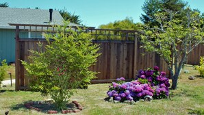 Une clôture en bois, un petit arbre et un parterre de fleurs aux fleurs violettes, le tout dans un jardin arrière.