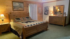 Ein Schlafzimmer im Chalet-Stil mit einem Bett, Nachttischen, einer Kommode und einem Deckenventilator.