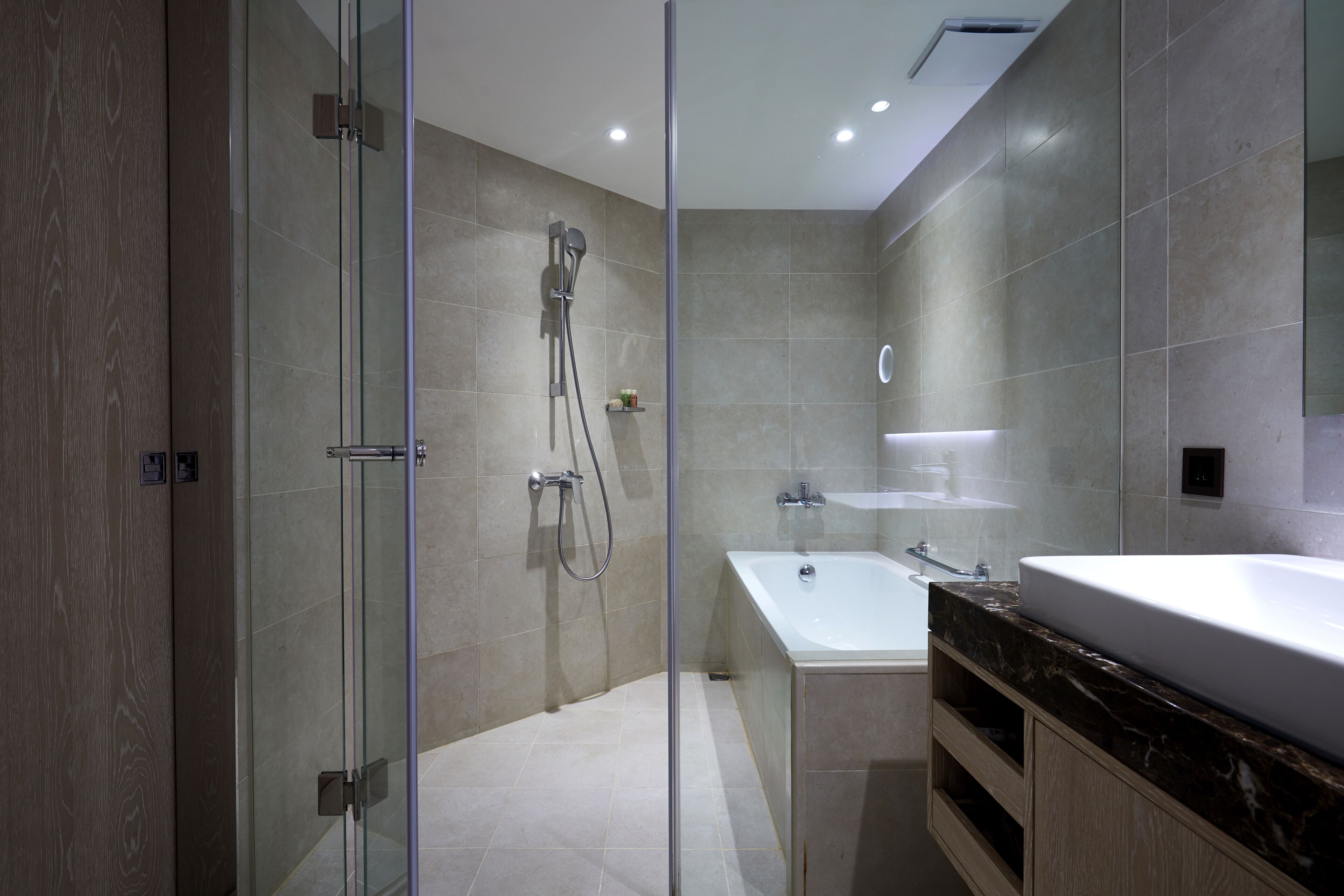 Un baño moderno con ducha de vidrio, una bañera independiente y un tocador con un espejo grande.