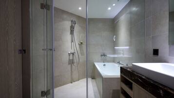 Un baño moderno con ducha de vidrio, una bañera independiente y un tocador con un espejo grande.