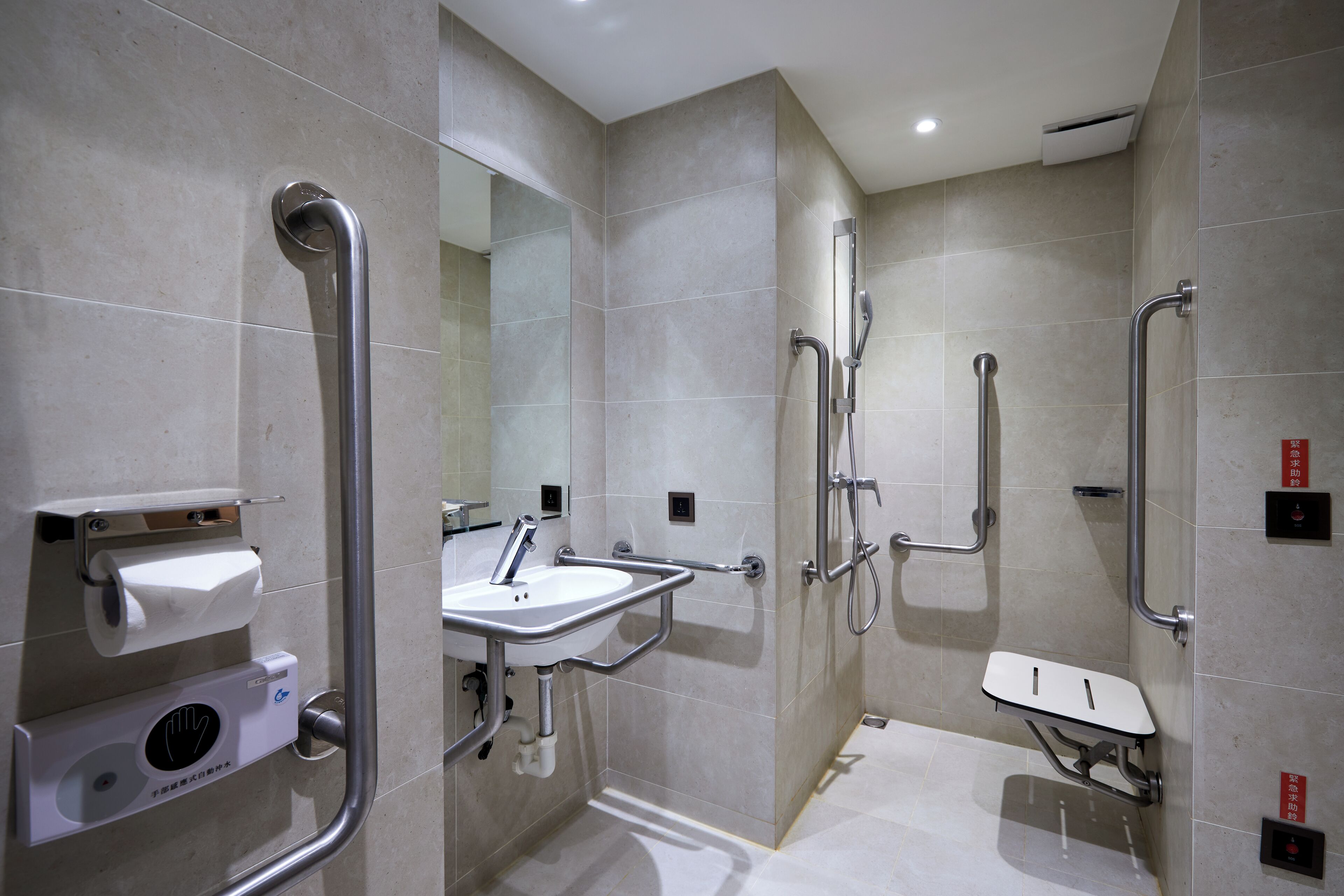 Un baño moderno con lavamanos, espejo y barras de apoyo.