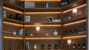 Eine moderne Bibliothek mit Bücherregalen, zwei blauen Sesseln und einem kleinen Tisch mit Büchern.