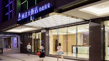 A hotel entrance with a modern glass facade and illuminated signage.
