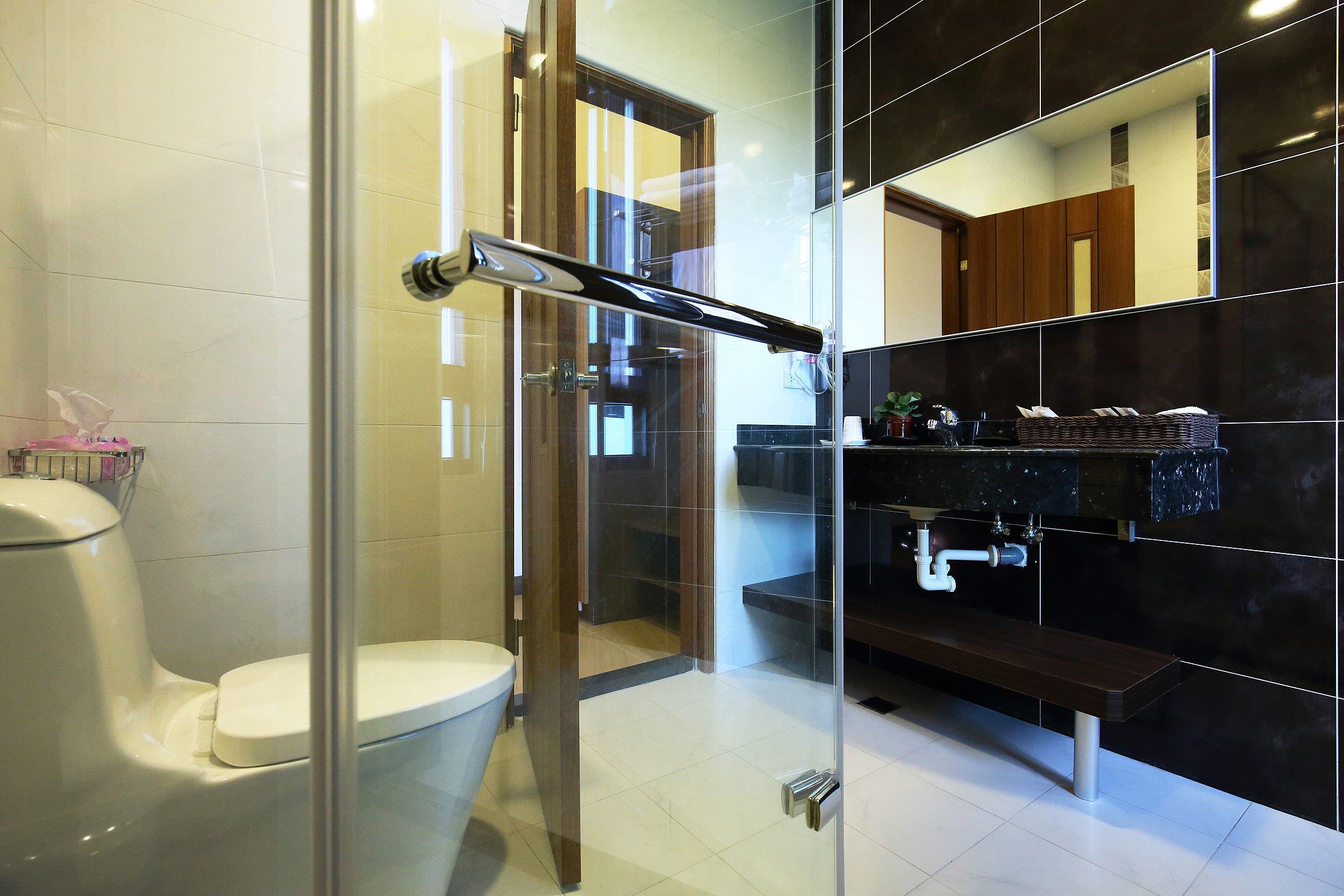 A modern bathroom with a glass shower enclosure, a toilet, and a vanity with a sink and mirror.