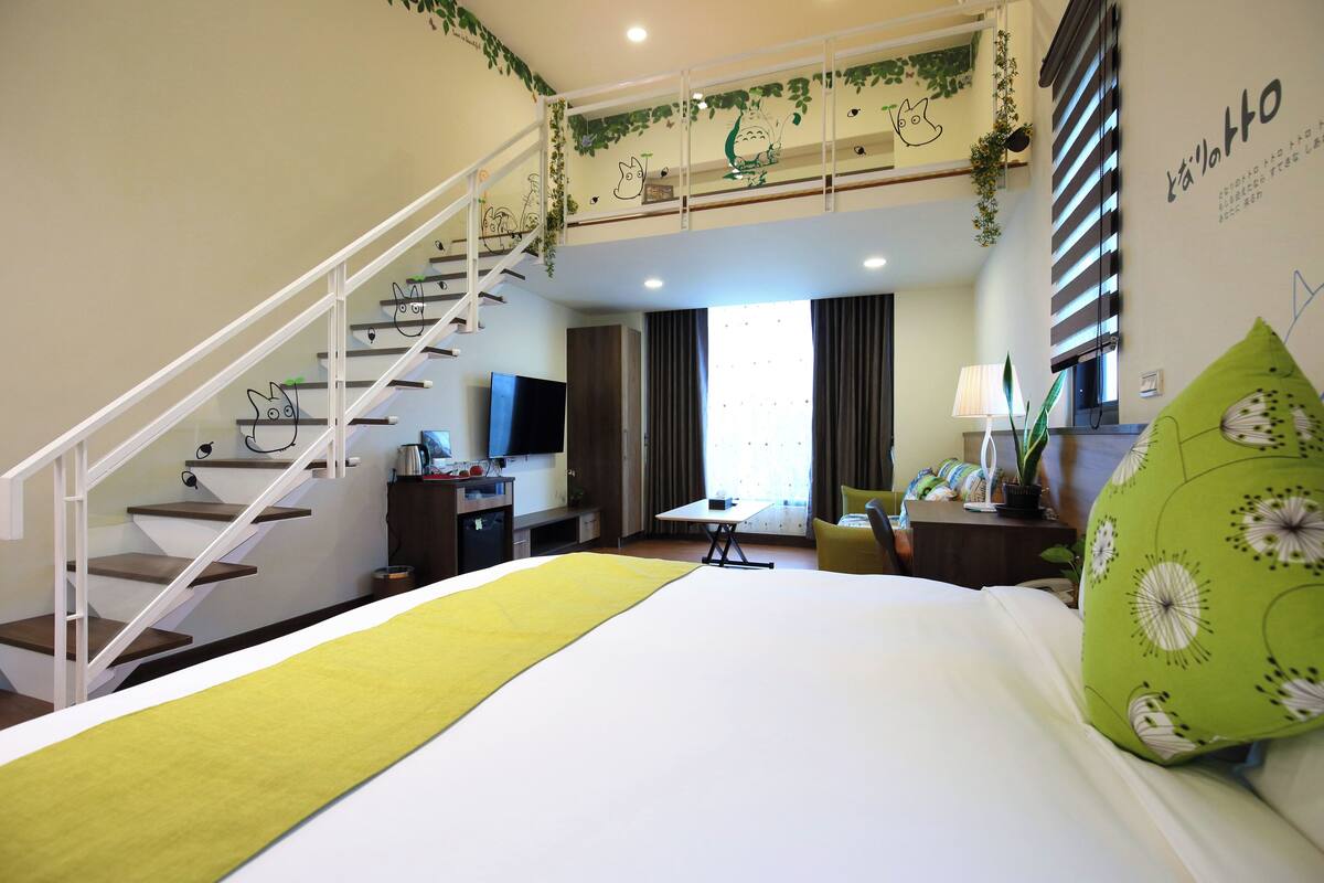 A hotel room with a bed, a desk, a chair, a TV, and a staircase.