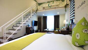 A hotel room with a bed, a desk, a chair, a TV, and a staircase.
