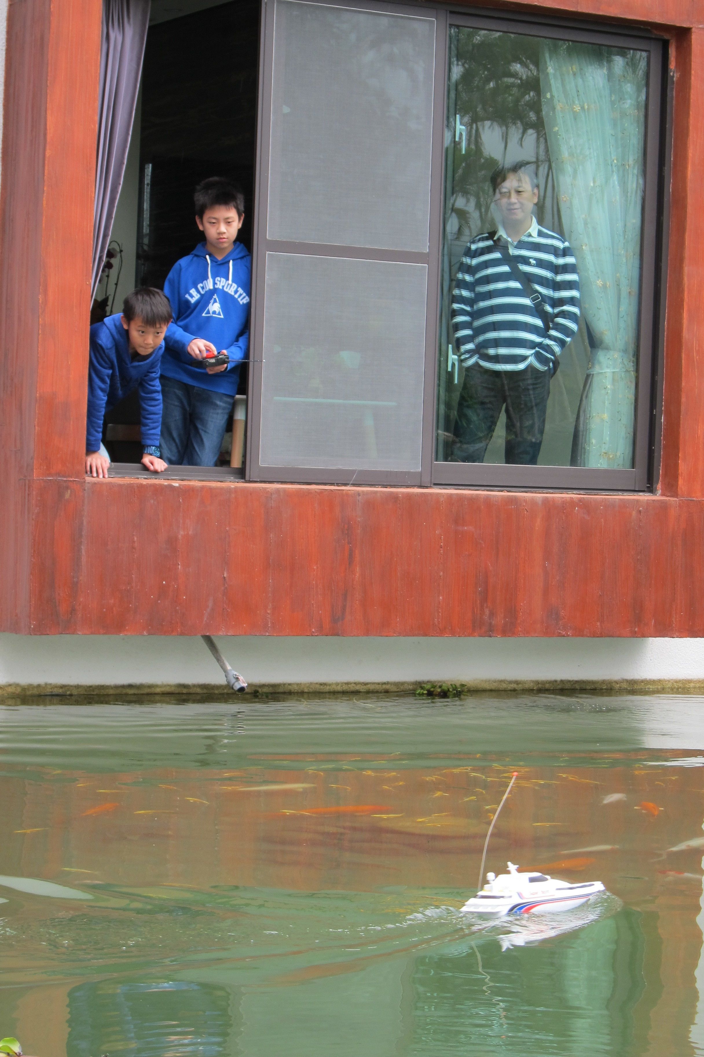 Un edificio con un gran ventanal y vistas a un cuerpo de agua con un barco.