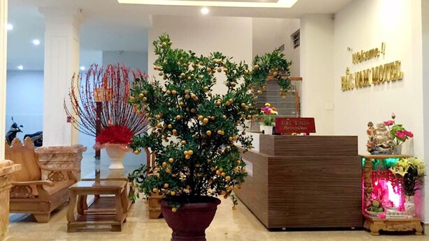 A reception area with a wooden reception desk, a large potted plant, and a welcome sign. - Bac Nam Motel (Da Nang)