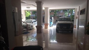 A clean, well-lit lobby with a tiled floor, a white car, and a motorcycle parked inside. - Bac Nam Motel (Da Nang)