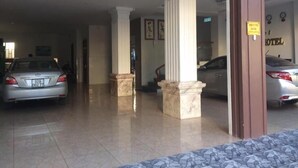 A hotel lobby with marble columns, a tiled floor, and parked cars. - Bac Nam Motel (Da Nang)