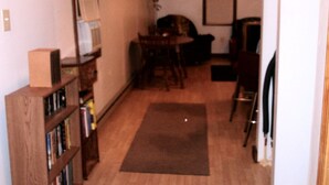 A living room with a wooden bookshelf, a dining table with chairs, a black and white striped rug, and a fireplace. - Small cabin in the woods Peaceful retreat (East Bernstadt)