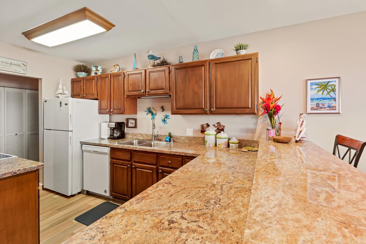 A kitchen with wooden cabinets, a granite countertop, a dishwasher, and a coffee maker.