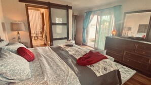 A bedroom with a bed, a dresser, a lamp, and a sliding glass door leading to a balcony. - Golf Course, Mnt Views, Balloons, King Bed, Veranda, Yard, 3 BD, WIFI, BBQ, WD (Albuquerque)