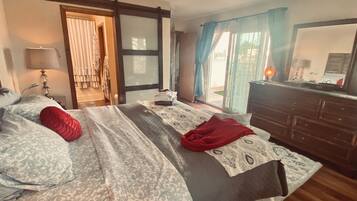 Une chambre à coucher comprenant un lit, une commode, une lampe et une porte-fenêtre coulissante donnant sur un balcon.