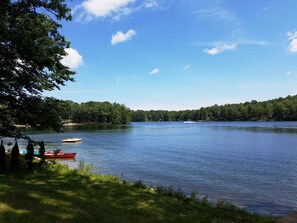 A calm lake with boats, surrounded by dense forest. - OPEN Cozy House on High Lake near TC! (Traverse City)