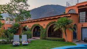 Zona de piscina con vista despejada a un edificio con arcos y una montaña al fondo.