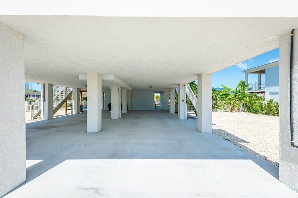 An empty building with a concrete floor and white walls, featuring a central open space and columns.