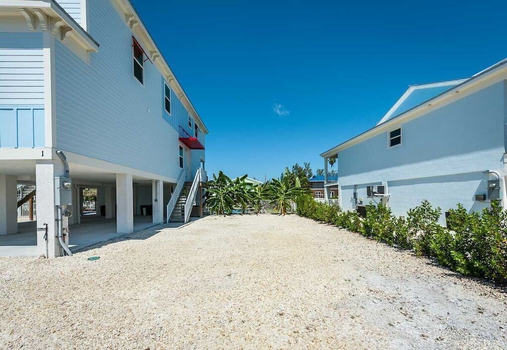 A building with a covered outdoor area, a gravel driveway, and a clear blue sky.