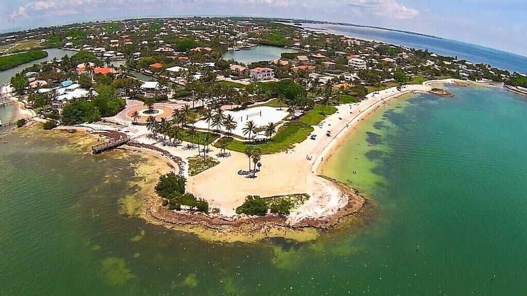 An aerial view of a coastal town with a beach, water bodies, and residential areas.