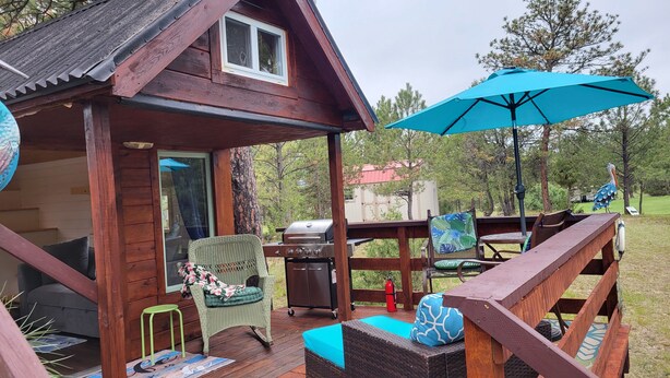 A wooden deck with outdoor furniture, a grill, and a blue umbrella.