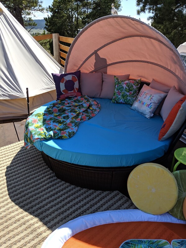 Un espacio al aire libre acogedor con una cama redonda, una tienda de campaña y una mesa de picnic.