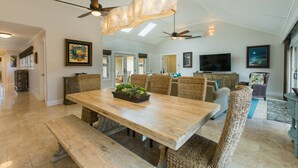 A spacious dining area with a large wooden table, wicker chairs, and a ceiling fan. - 5 Star, Great for Families, 4BD w/AC, HTD Pool, Poipu Beach Athletic Club access (Koloa)