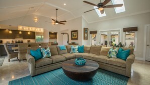 A spacious living room with a large sectional sofa, a round coffee table, and a ceiling fan. - 5 Star, Great for Families, 4BD w/AC, HTD Pool, Poipu Beach Athletic Club access (Koloa)