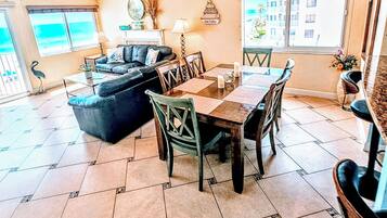 A spacious living area with a dining table, chairs, a sofa, and a ceiling fan.