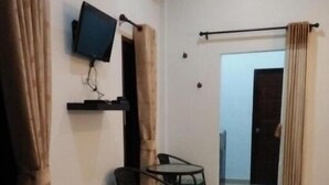 Ein Zimmer mit Fernseher an der Wand, einem kleinen Tisch mit zwei Stühlen und einer Tür zu einem anderen Raum.