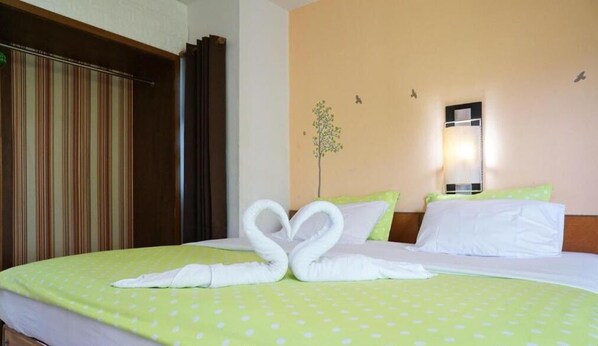 A hotel room with a bed, striped curtains, a wall-mounted light, and a wall decoration of a tree and butterflies. - Arcadian Resort (Krabi)