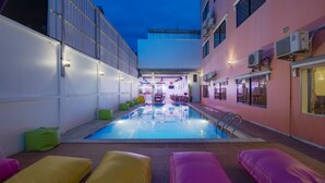 An indoor swimming pool with a view of the cityscape, surrounded by colorful seating areas and modern architecture. - The Siem Reap Chilled Backpacker (Siem Reap)