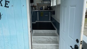 Una escalera estrecha conduce a una cocina con microondas, lavaplatos y armarios.