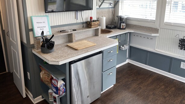 Una cocina equipada con microondas, cafetera y televisor sobre la encimera.