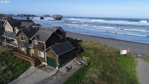 Una propiedad costera con varias casas, una playa de arena y afloramientos rocosos al fondo.
