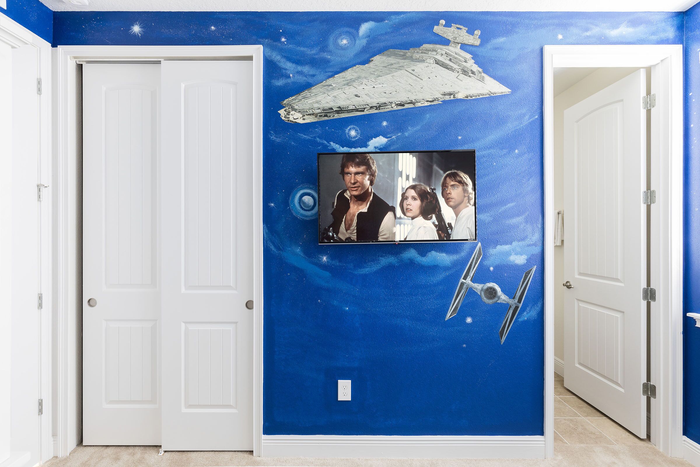 A hallway with a blue wall featuring a Star Wars-themed mural, including a spaceship and characters.