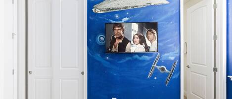 A hallway with a blue wall featuring a Star Wars-themed mural, including a spaceship and characters.