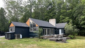 A modern house with a large deck, a chimney, and a well-maintained lawn. - Perfectly located on the Mountain rd between Stowe village and Stowe Mountain (Stowe)