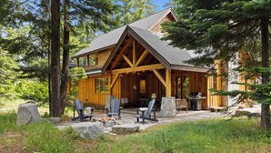 A log cabin with a covered porch, outdoor seating, and a stone fire pit. - Suncadia Retreat • 3 porches • Quiet Cul-de-Sac • Fire pit • Bikes (Cle Elum)
