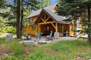 A log cabin with a covered porch, outdoor seating, and a stone fire pit.