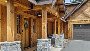 A wooden cabin with a stone foundation, a garage, and a covered porch area. - Suncadia Retreat • 3 porches • Quiet Cul-de-Sac • Fire pit • Bikes (Cle Elum)
